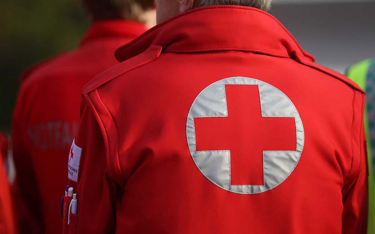 Personne en uniforme avec logo de la Croix-Rouge au dos.