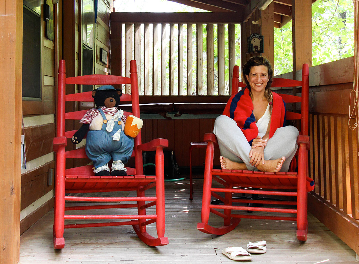 Laura Cano sitting on a red swing on a porch.