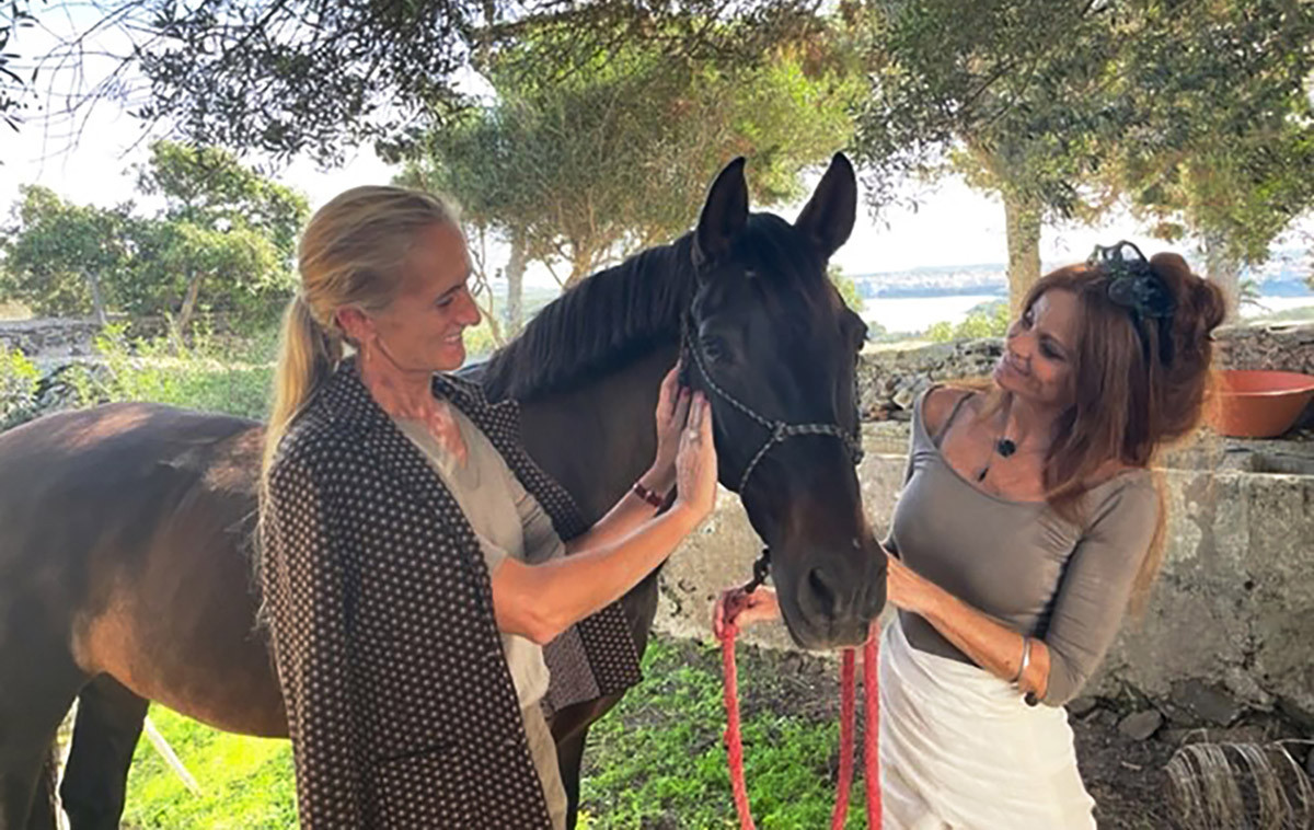 Cristine Bedfor and Sita Moll caressing a horse in the field.
