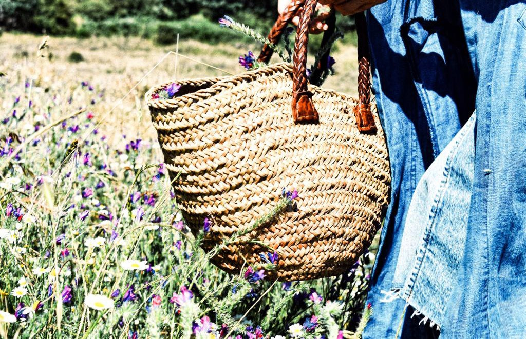 Wicker basket with flowers in a field.